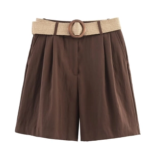 Detail view of high-waist brown Bermuda shorts featuring front pleats and woven belt