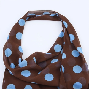 Detailed view of lightweight brown scarf featuring large light blue polka dot pattern