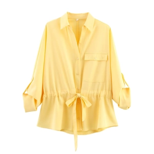 Detail of yellow long sleeve shirt featuring drawstring waist and rolled buttoned cuffs
