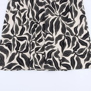 Linen blend halter dress featuring black and white abstract leaf print on beige base