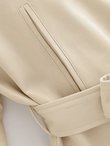 Close-up of khaki trench coat detail showing belt loop and high-quality twill fabric
