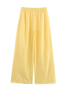Detail view of high-waist yellow wide-leg trousers in smooth satin fabric with elastic waist