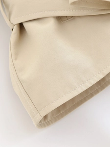 Close-up of beige trench coat twill fabric with reinforced stitching and belt detail