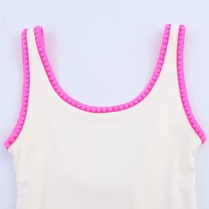 Detailed close-up of pink scalloped embroidered trim on a cream-colored swimsuit top