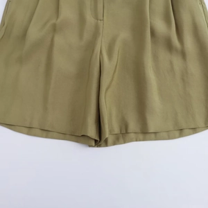 Detail of olive green high-waisted Bermuda shorts with elegant pleats and soft fabric