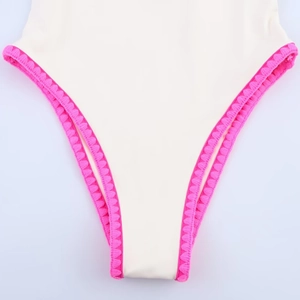 Detailed close-up of rose pink scalloped edge embroidery on off-white swimwear fabric