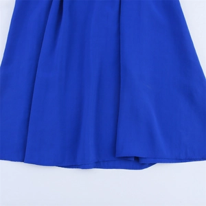 Gros plan du tissu bleu roi d'une robe midi montrant le drapé fluide et les coutures fines