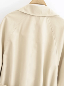Detail shot of beige trench coat back collar and raglan sleeve stitching on wooden hanger