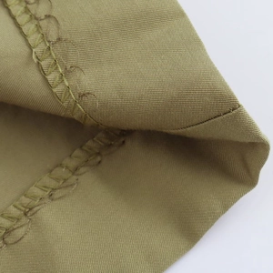 Detailed close-up of premium overlock stitching on khaki cotton twill Bermuda shorts