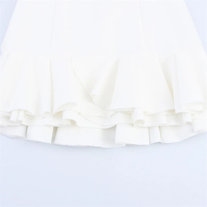 Detailed close-up of double-layered ruffle hem on a white woven spring dress