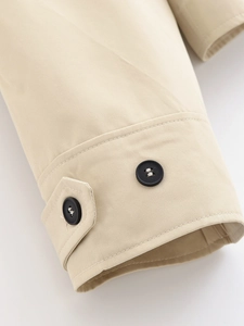 Detail of beige jacket cuff with twill fabric texture and black decorative buttons