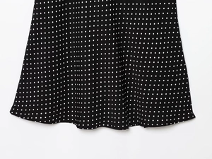 Detail of white polka dot pattern on black fabric with hem stitching on the dress