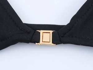 Detail of a polished gold rectangular metal clasp on high-quality black bikini fabric