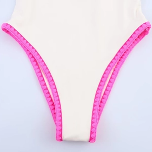 Close-up of off-white one-piece swimsuit with vibrant pink scalloped crochet trim edges