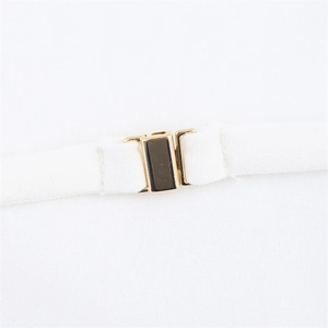 Detailed close-up of golden metal rectangular fastener on white halter neck dress strap
