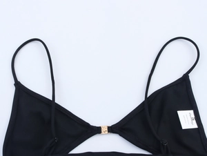 Detail of black bikini top with gold metal buckle and washing label showing size S