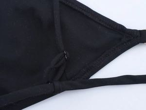 Detail of adjustable black bikini shoulder strap with metal slider and reinforced stitching