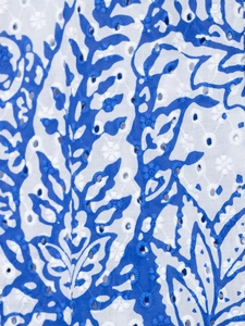Vue macro d'une broderie florale bleue et blanche avec motif ajouré détaillé