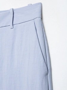 Detailed view of the light blue trousers waist featuring belt loops and side pockets