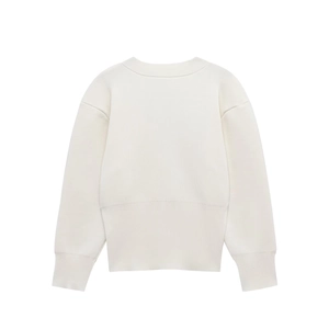Detailed close-up of cream knit sweater showing wide ribbed cuffs and fine cotton texture