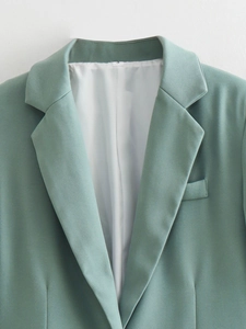 Close-up of mint green blazer lapel with single button and white lining detail
