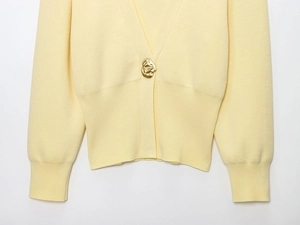 Detailed shot of yellow knit cardigan with oversized textured gold metal button and ribbed waist