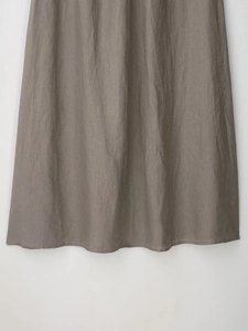 Detailed macro view of the taupe linen blend fabric texture and hem stitching on the skirt