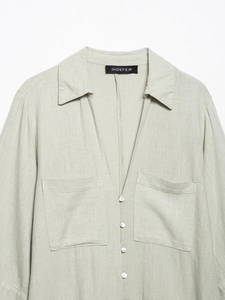 Detail of light green linen shirt dress showing V-neck, collar and chest pockets