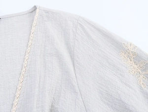 Close-up of beige floral embroidery and lace trim on a breathable linen-blend shirt