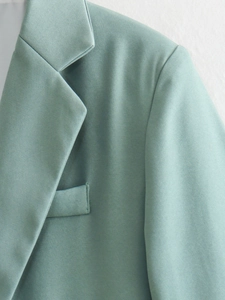 Detail of sage green blazer showing notch lapel and pocket with twill fabric texture