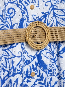 Détail de robe d'été avec broderie florale bleue, boutons bois et ceinture en paille