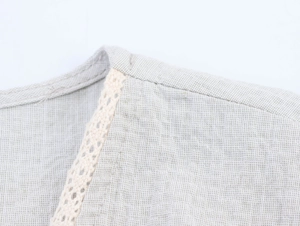 Close-up of beige linen shirt with floral lace embroidery and fine texture detail