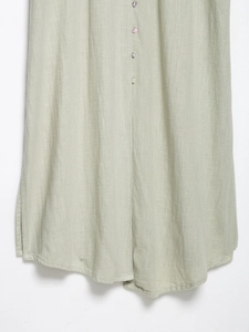 Detailed macro view of sage green linen fabric texture with pearlescent shell buttons
