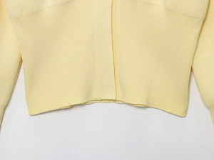 Detailed close-up of light yellow knit cardigan with ribbed hem and soft texture