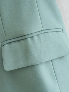 Close-up of mint green blazer flap pocket showing high-quality stitching and twill fabric