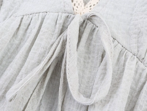 Macro detail of breathable linen shirt with cotton lace trim and adjustable tie knot