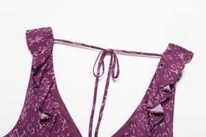 Detailed view of dark purple floral print fabric with ruffle edges and a tie-up bow design