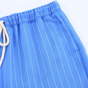 Detail of blue striped trousers featuring elastic waist and cotton drawstring closure