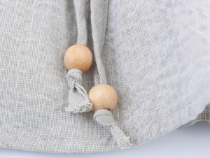 Close-up of linen fabric texture and drawstring with natural wooden beads detail