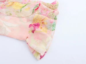 Dettaglio in primo piano del tessuto in chiffon floreale rosa con bordi a balze
