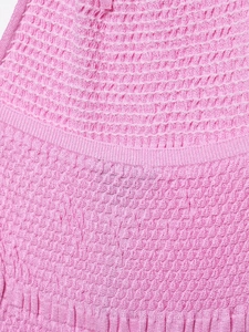 Detail shot of the candy pink knitted fabric with smocked elastic texture and waffle weave