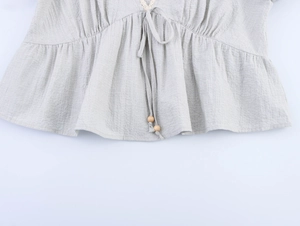 Detailed macro view of linen texture shirt with lace trim and wooden bead drawstrings
