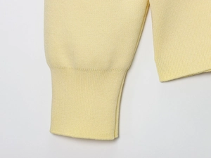 Detail view of high-quality yellow knit cardigan featuring premium ribbed cuff texture