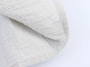 Macro shot of natural linen fabric texture with clean rolled hem stitching on a beige shirt