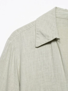 Detail of minimalist light sage linen shirt dress with classic collar and fine texture