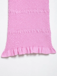 Detailed macro view of pink smocked elastic fabric texture with a ruffled hem finish