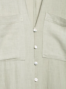Detail of light green linen dress showing V-neckline, shell buttons and square pockets