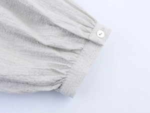 Detail of elegant pleated cuff with shell button on beige linen blend blouse shirt