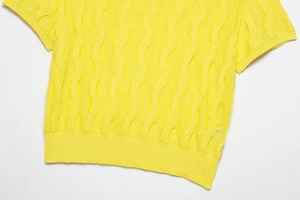 Detail of bright yellow knit top showing vertical wavy texture and ribbed hem fabric