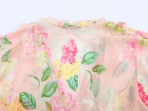 Dettaglio macro della camicia in chiffon floreale con collo a balze e motivi di fiori